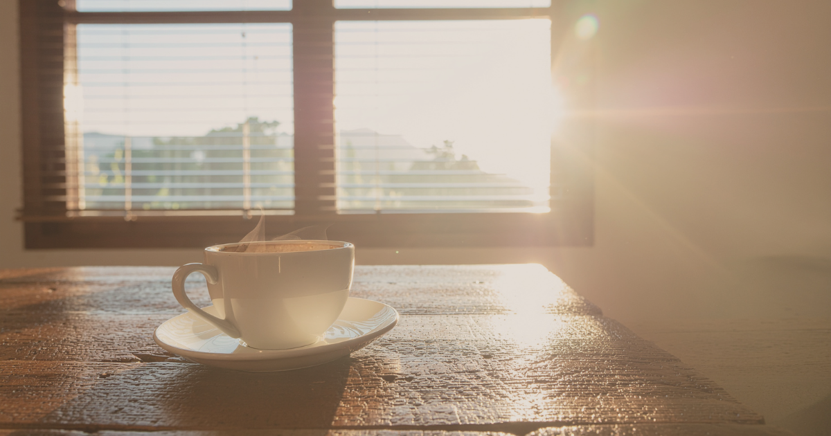 a cup of coffee sits on a table in front of a window