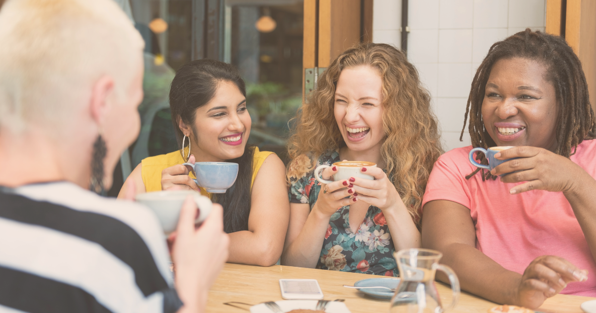 Four friends enjoying coffee and pastries at a table.