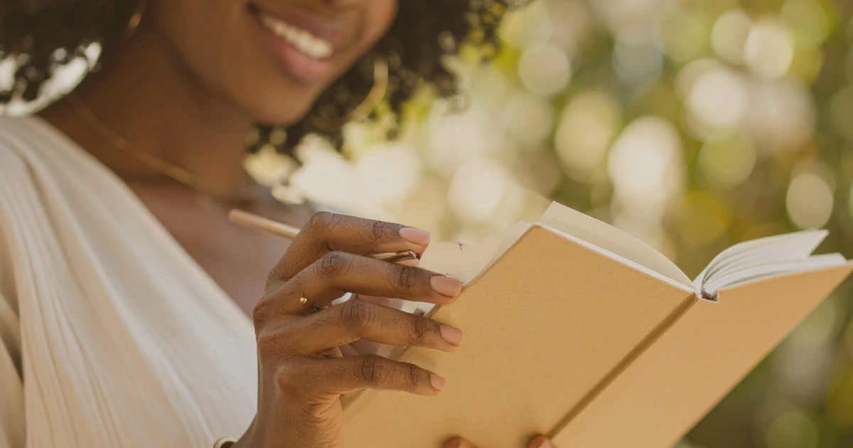 A woman is smiling while holding an open book